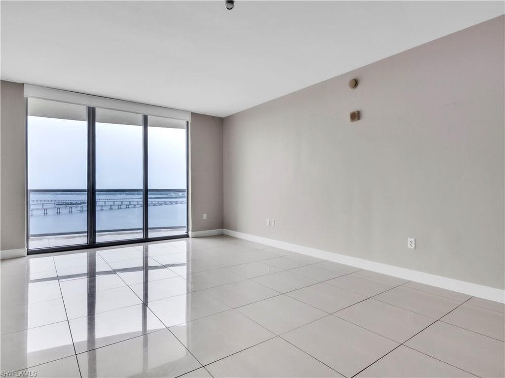 Empty room featuring light tile patterned floors and expansive windows