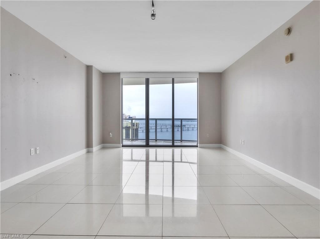 Spare room with a wall of windows and light tile patterned floors