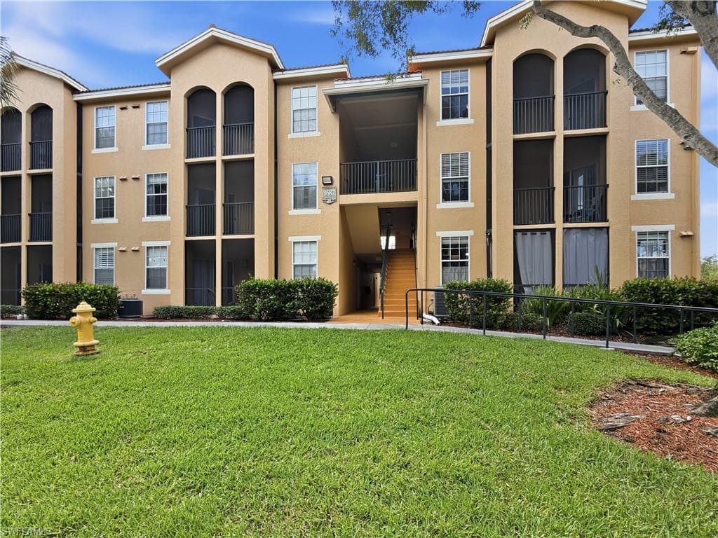 Three-story residential building featuring stucco exterior and multiple screened balconies