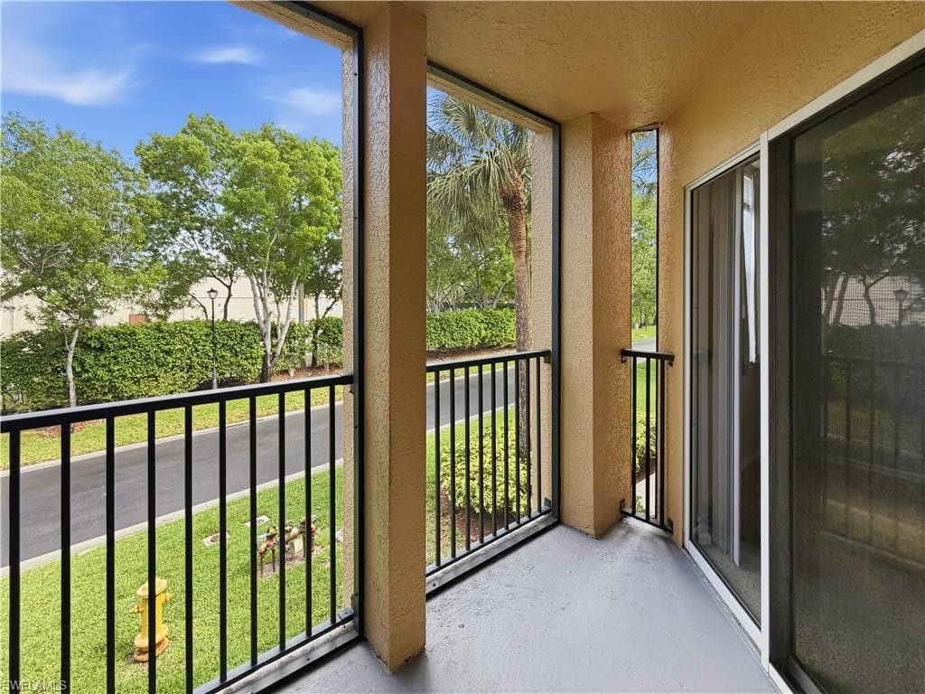 Private balcony featuring a painted concrete floor, black metal railings, and a sliding glass door