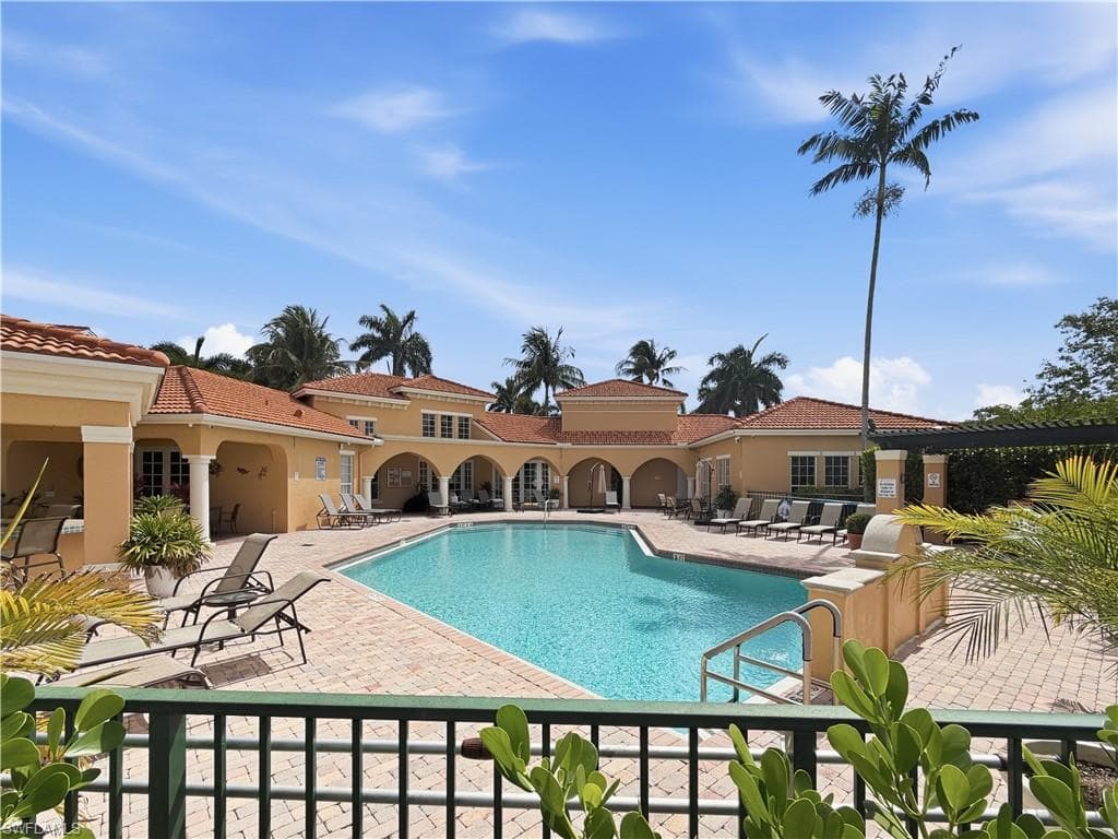 Resort-style pool area featuring a large swimming pool, surrounding paver patio, and Mediterranean-inspired architecture with arched loggias