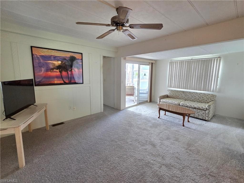 Living room with NEW neutral carpet and ceiling fan. Lots of natural light throughout this home.