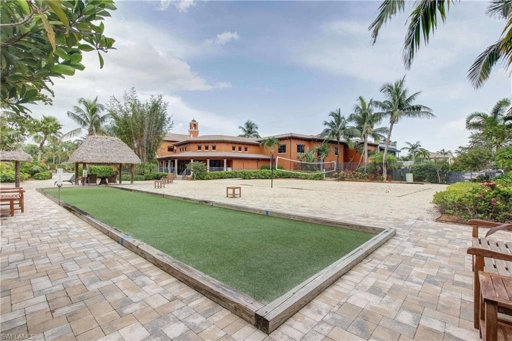 Outdoor recreational space featuring a bocce ball court with artificial turf surface, a sand volleyball court, and a thatched-roof cabana