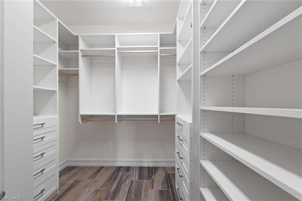 Custom closet system featuring white cabinetry, varied shelving, integrated drawers with brushed nickel hardware, hanging rods, and wood-finish flooring. NEW INSPIRED CLOSETS CUSTOM CLOSET ORGANIZERS (2018), NEW TILE FLOOR (2018)