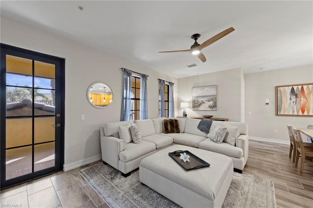 Living area featuring wood-finish tile flooring, a dark-framed glass paneled door, and a modern ceiling fan. NEW TILE FLOOR (2018)