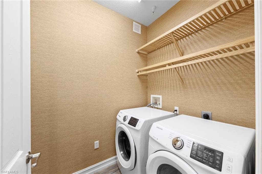 Dedicated laundry area featuring textured wall finish, wood-finish shelving, and wood-finish flooring. NEW TILE FLOOR (2018), NEW WASHER/DRYER (2018), NEW WALLPAPER (2018)