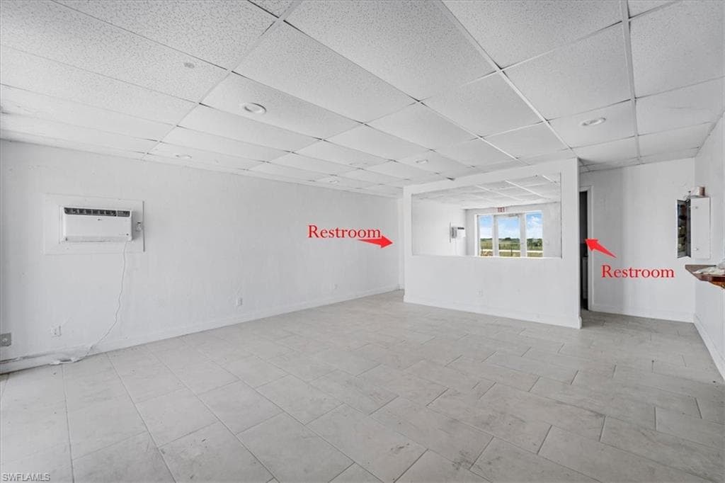 Spacious interior featuring light tile flooring, white walls, and a drop ceiling with recessed lighting