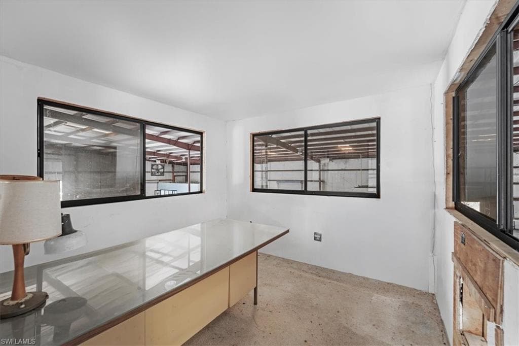 White-painted interior with multiple black-framed windows providing expansive views of an industrial-style structure