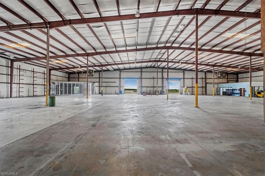 Spacious industrial warehouse featuring concrete flooring, exposed steel beam construction, metal ceiling, and multiple large bay doors