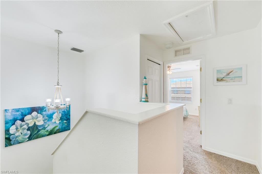Upper-level hallway featuring textured carpeting, white painted walls, and an overhead light fixture