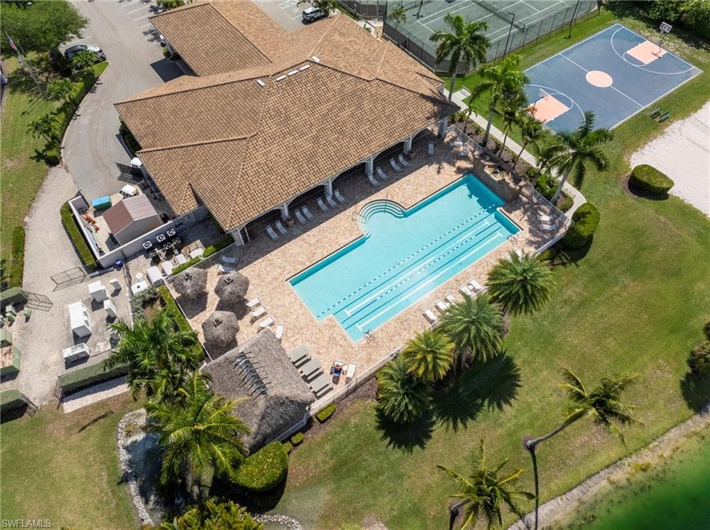 Expansive community amenities featuring a large swimming pool with lap lanes, surrounding paver decking, and adjacent tennis/pickleball courts