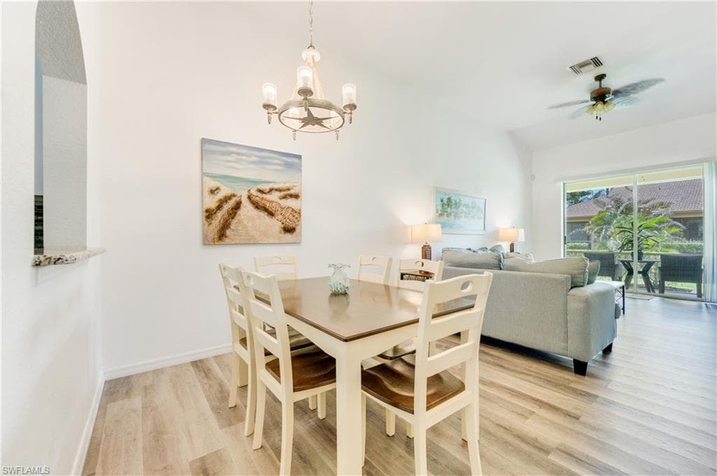Open-concept living space featuring wood-finish flooring, a contemporary chandelier, and an arched pass-through window with a granite ledge