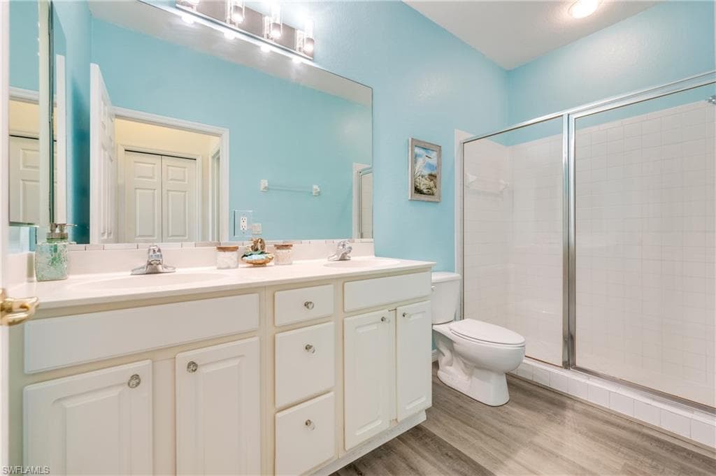 Bathroom featuring a double vanity with white cabinetry and chrome fixtures, a large mirror, a separate shower with a glass doors