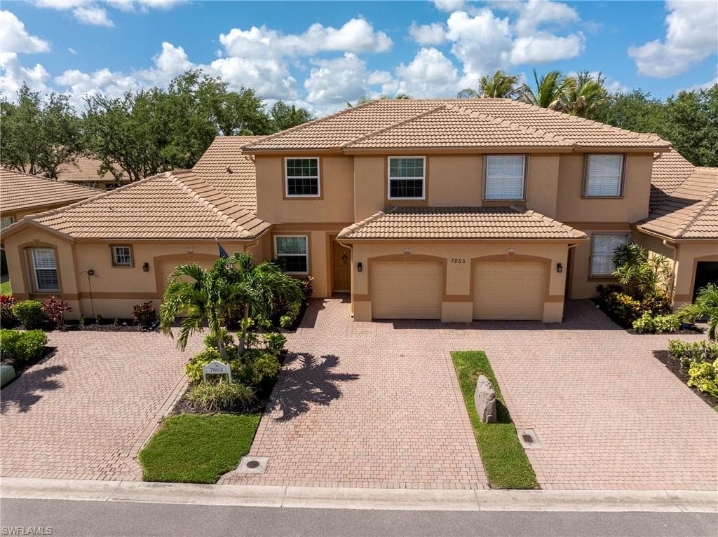 Mediterranean-style residence featuring a tile roof, stucco exterior, private garage, and a paver driveway