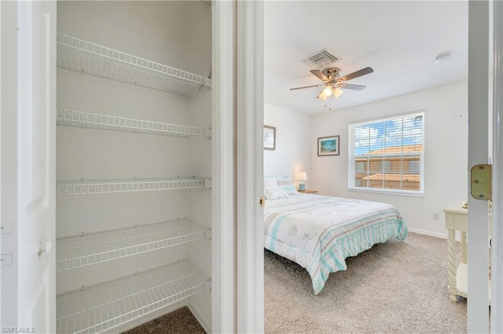 Bedroom featuring a ceiling fan with integrated lighting, a window with horizontal blinds, and carpeting
