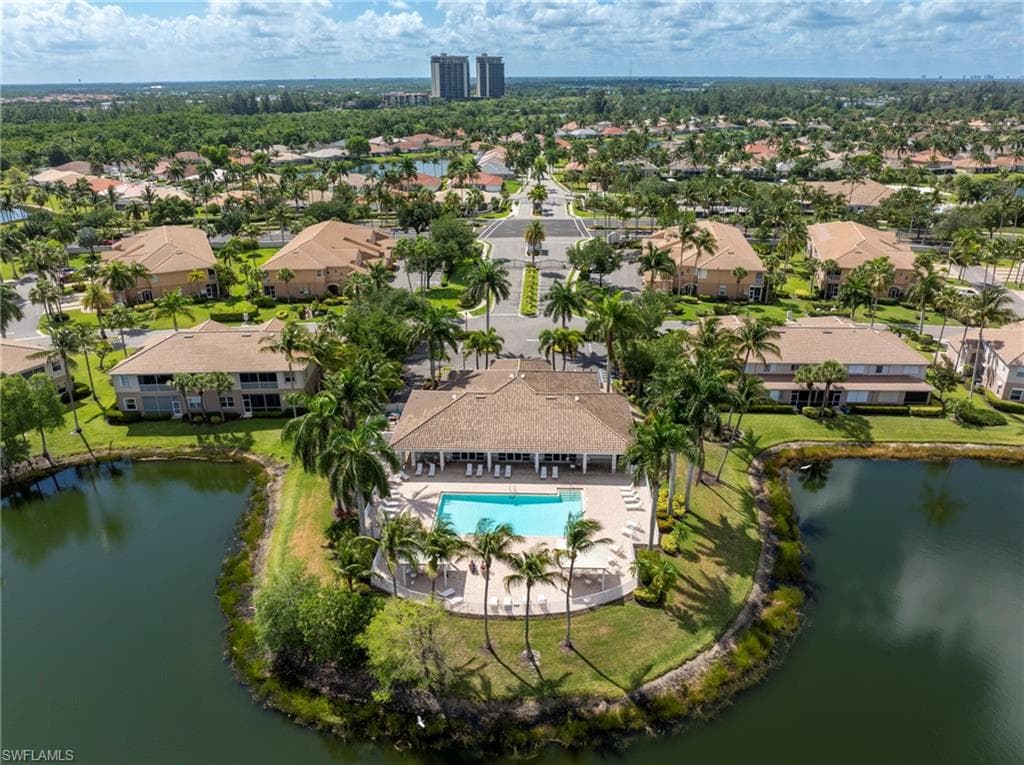 Community clubhouse with an outdoor swimming pool, surrounded by mature palm trees and green landscaping