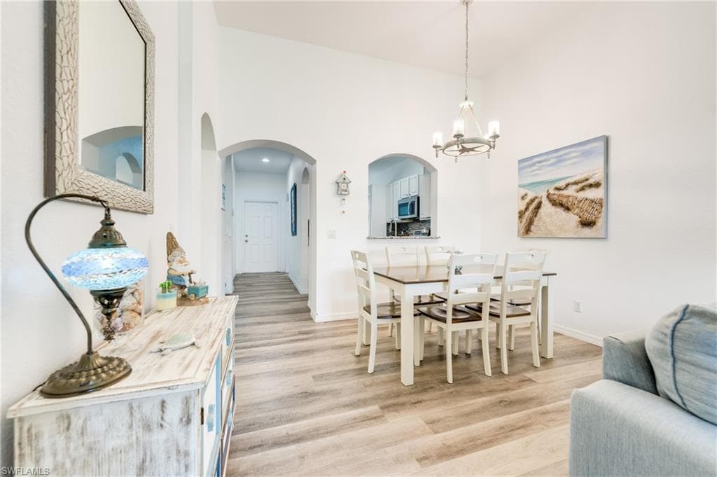 Vaulted ceilings accentuate this dining area, featuring wood-finish flooring and a contemporary chandelier