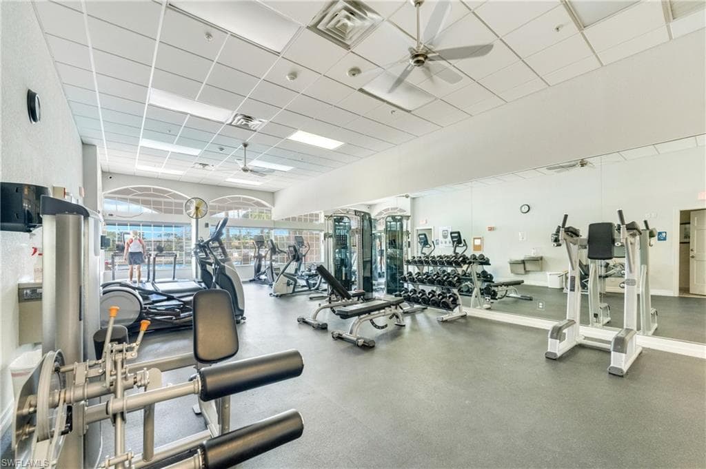 Spacious fitness center featuring a variety of exercise equipment, rubberized flooring, and mirrored walls