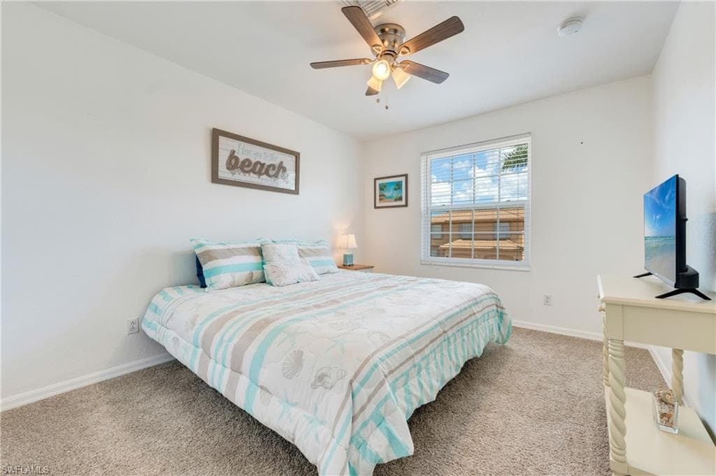 Carpeted guest room featuring a ceiling fan with integrated lighting, a window with horizontal blinds, and white baseboards