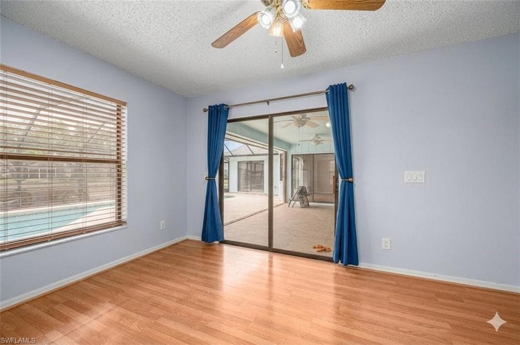 Room featuring wood-finish flooring, a ceiling fan with integrated lighting, and light blue wall paint