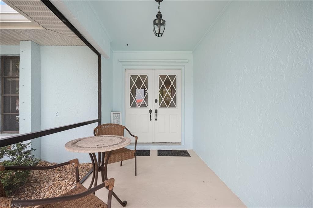 Covered entry porch featuring white double doors with diamond-pane glass inserts