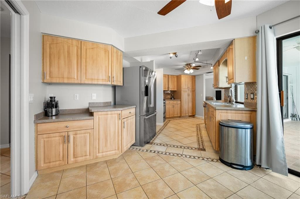 Kitchen featuring light wood-finish cabinetry, neutral countertops, and a full stainless steel refrigerator