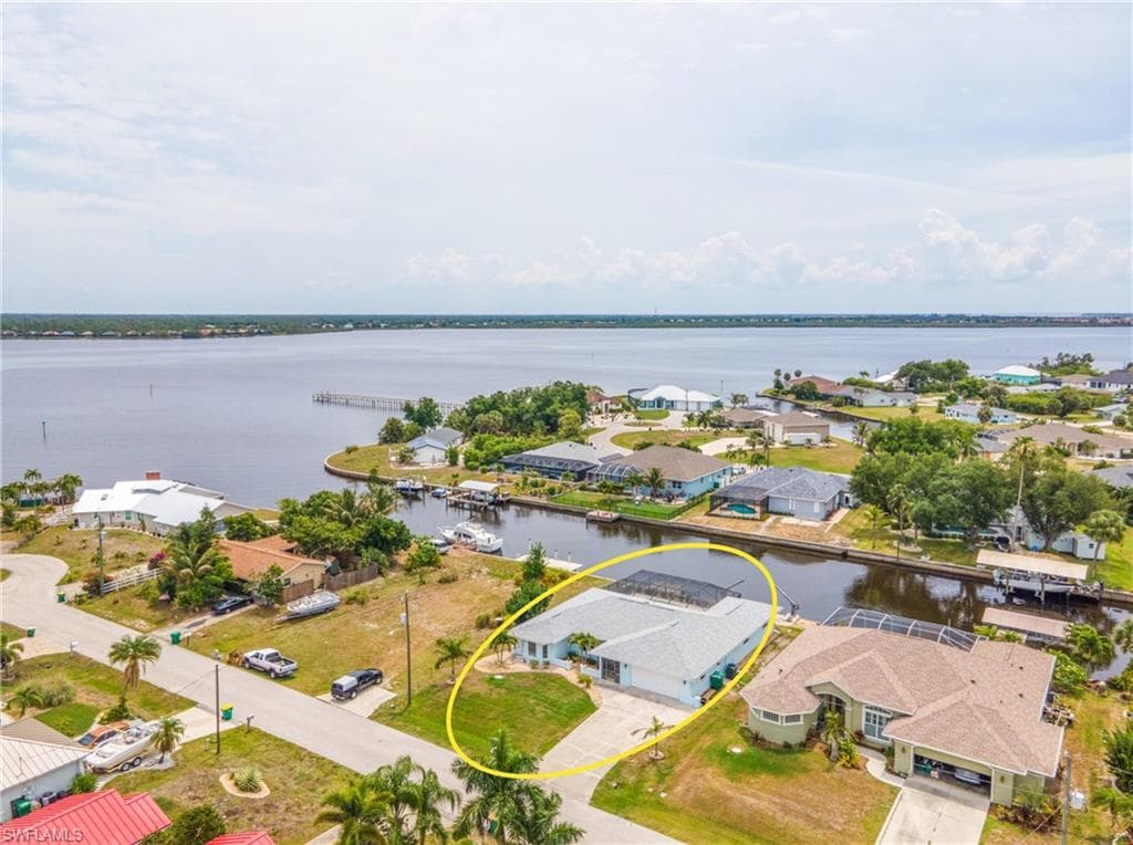 Waterfront property featuring a screened-in pool enclosure, private boat dock, and direct canal access