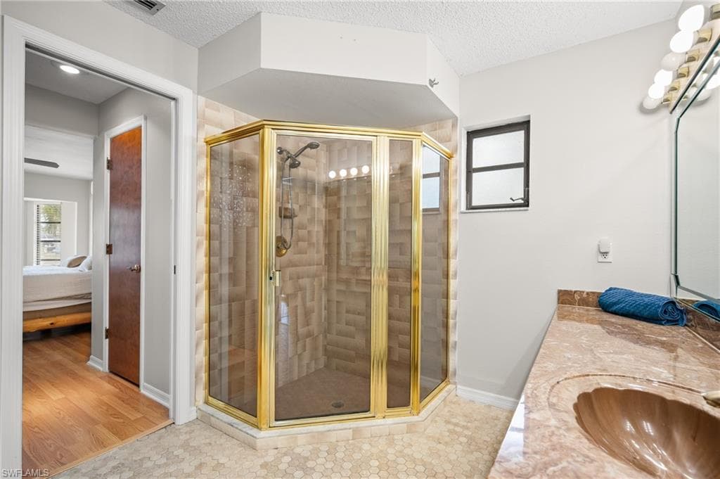 Gold-framed glass shower enclosure with patterned wall tile and hexagon floor tile