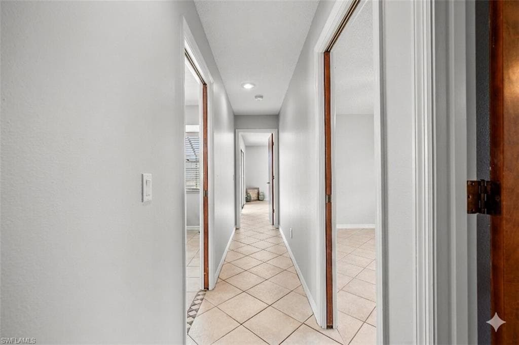 Central hallway featuring diagonal tile flooring, recessed lighting, and multiple doorways with wood trim