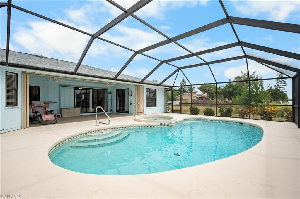 Screened enclosure featuring a freeform swimming pool with integrated spa and concrete decking