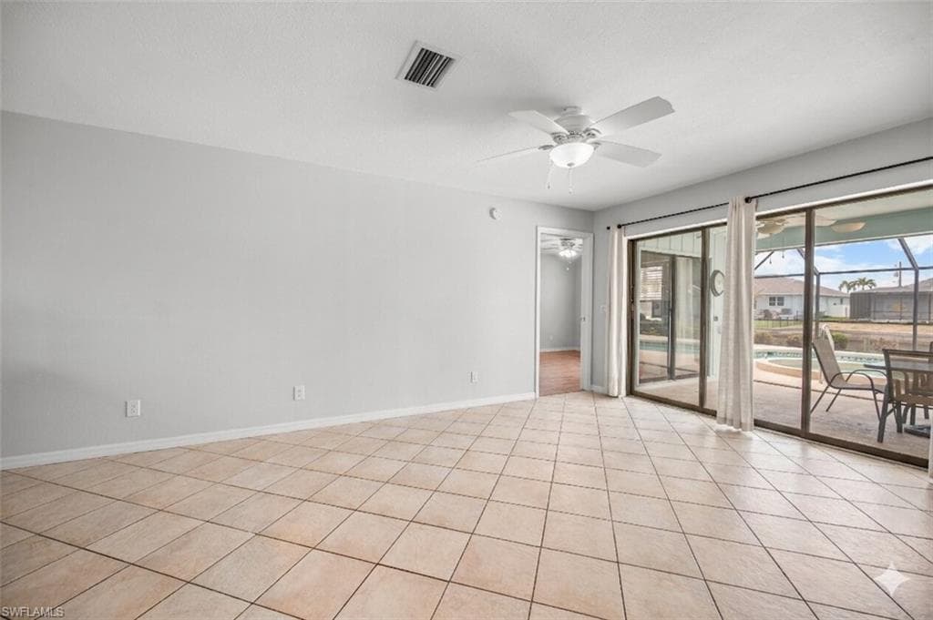 Tiled flooring throughout this open space, featuring multiple sliding glass doors opening to the screened patio with a pool