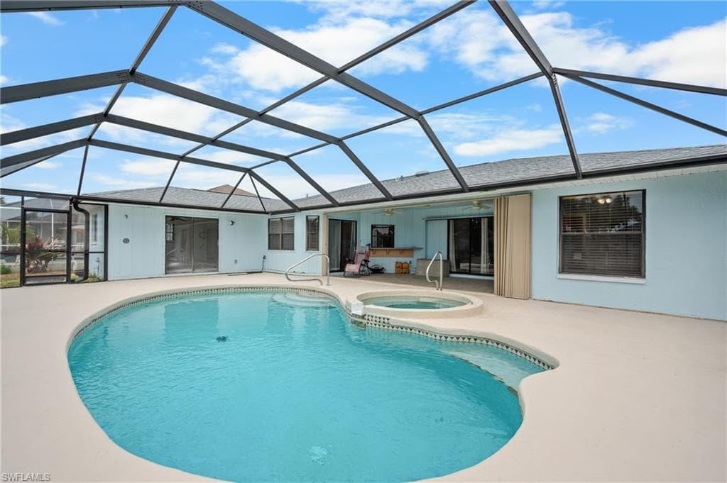 Screened enclosure featuring a free-form pool with integrated spa and extensive concrete decking