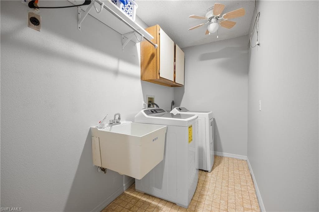 Dedicated laundry space featuring a utility sink, upper cabinetry, and a ceiling fan