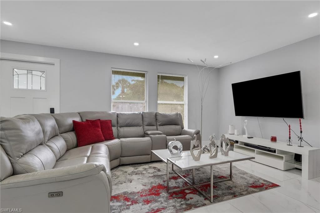 Spacious living area featuring recessed lighting, light-toned walls, and large format tile flooring