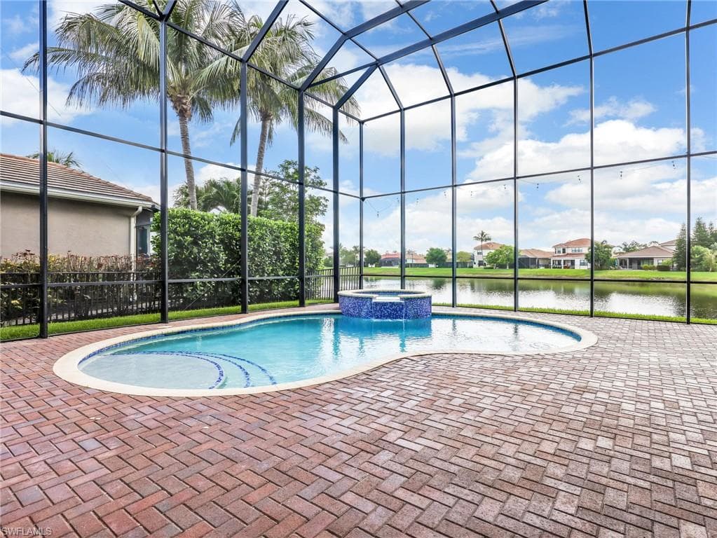 Screened lanai featuring a freeform swimming pool with integrated spa and brick paver decking