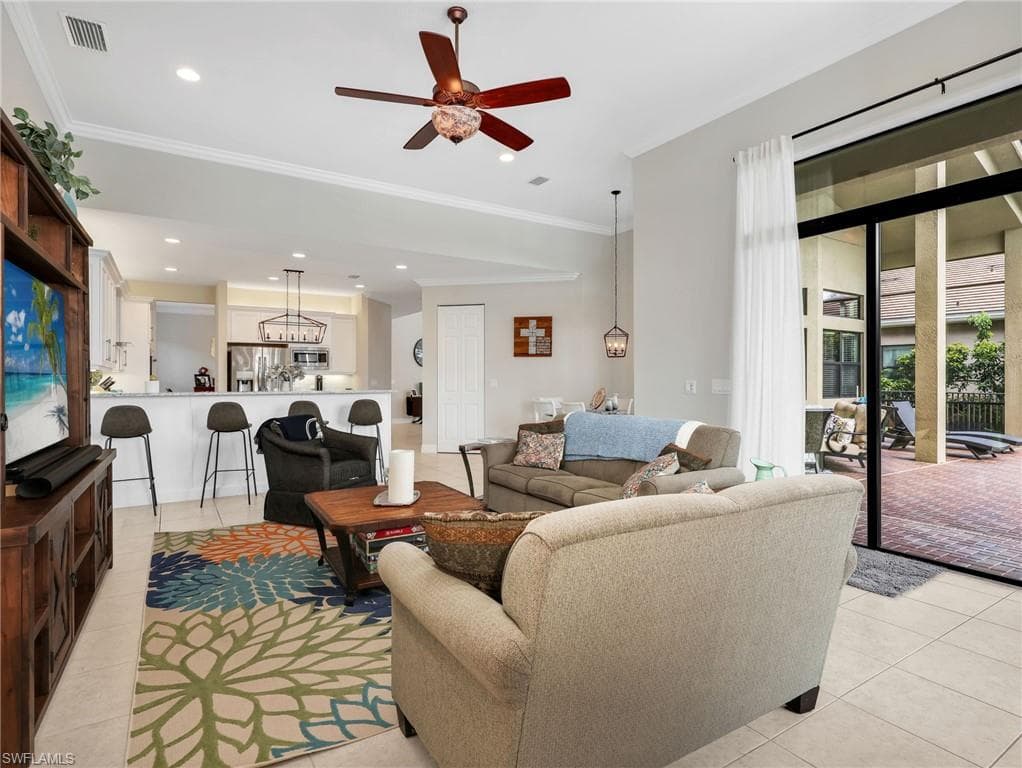 Open-concept living area with tile flooring and crown molding