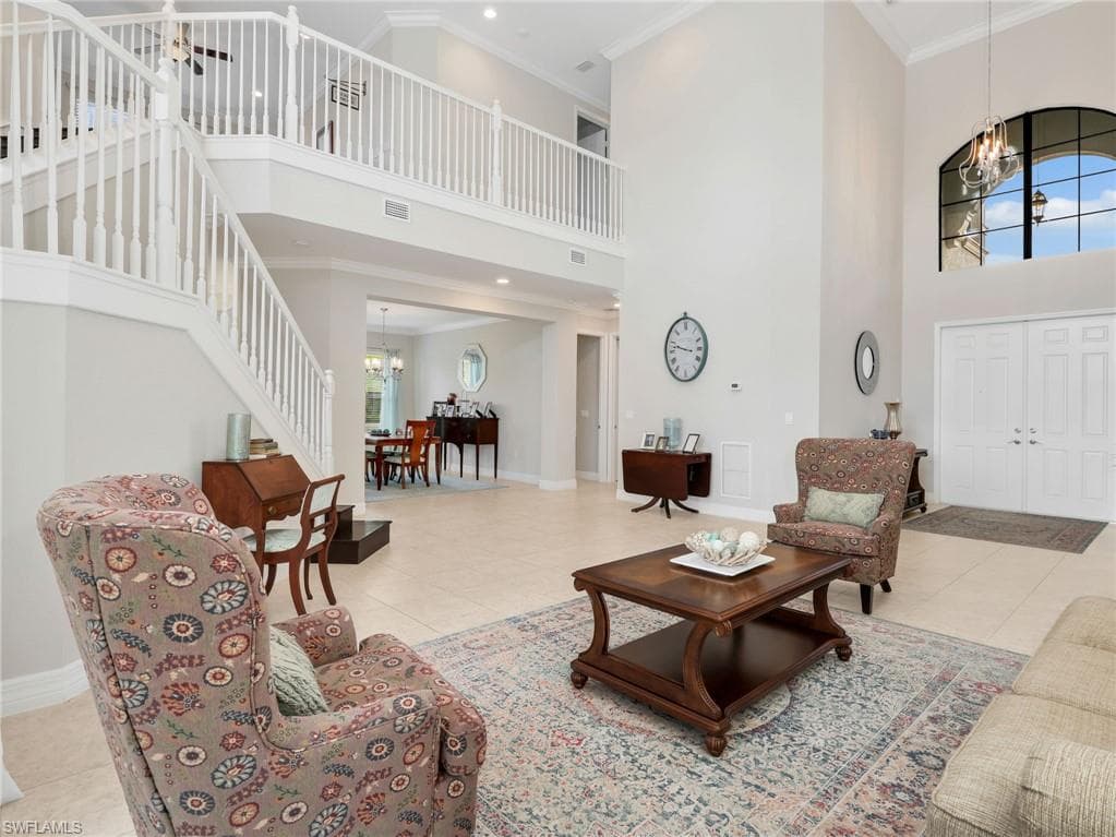 Grand foyer featuring a dramatic two-story ceiling, a sweeping staircase with white balusters, and elegant double entry doors