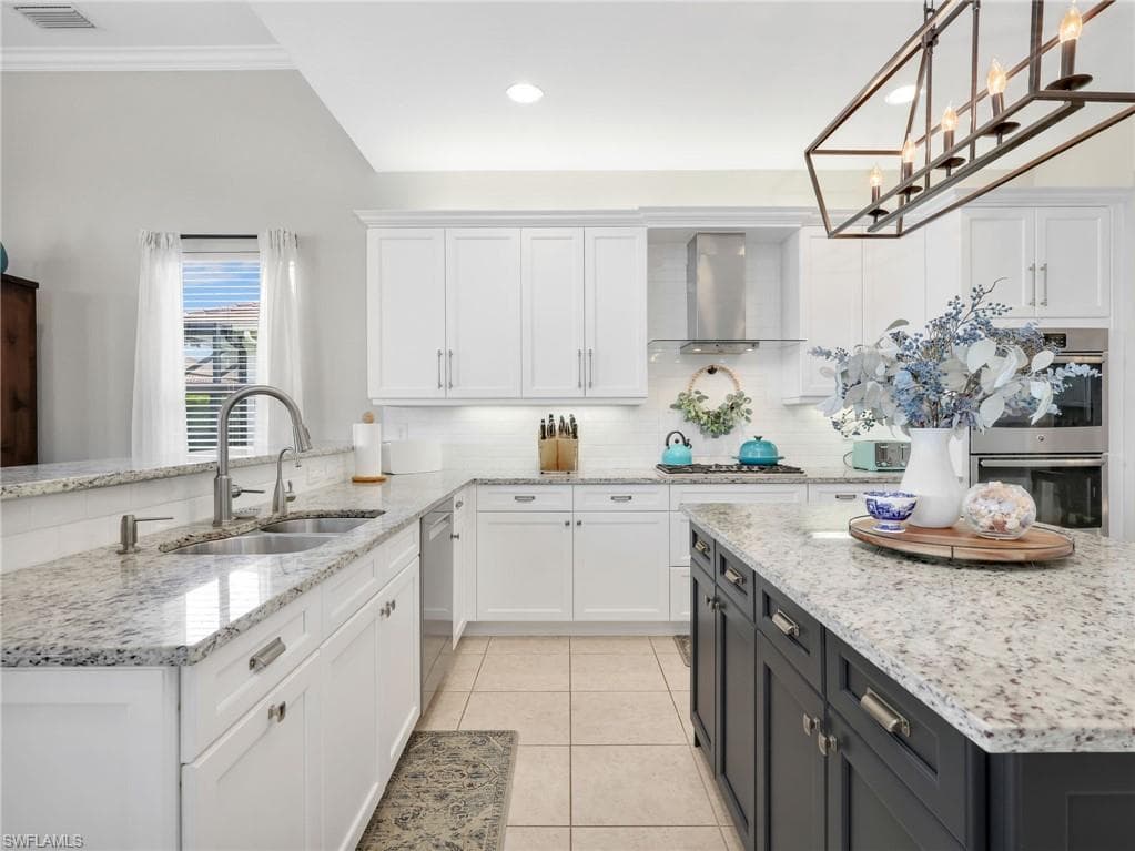 Kitchen featuring white shaker cabinetry, granite countertops, tile flooring, stainless steel appliances, and a central island with dark cabinetry