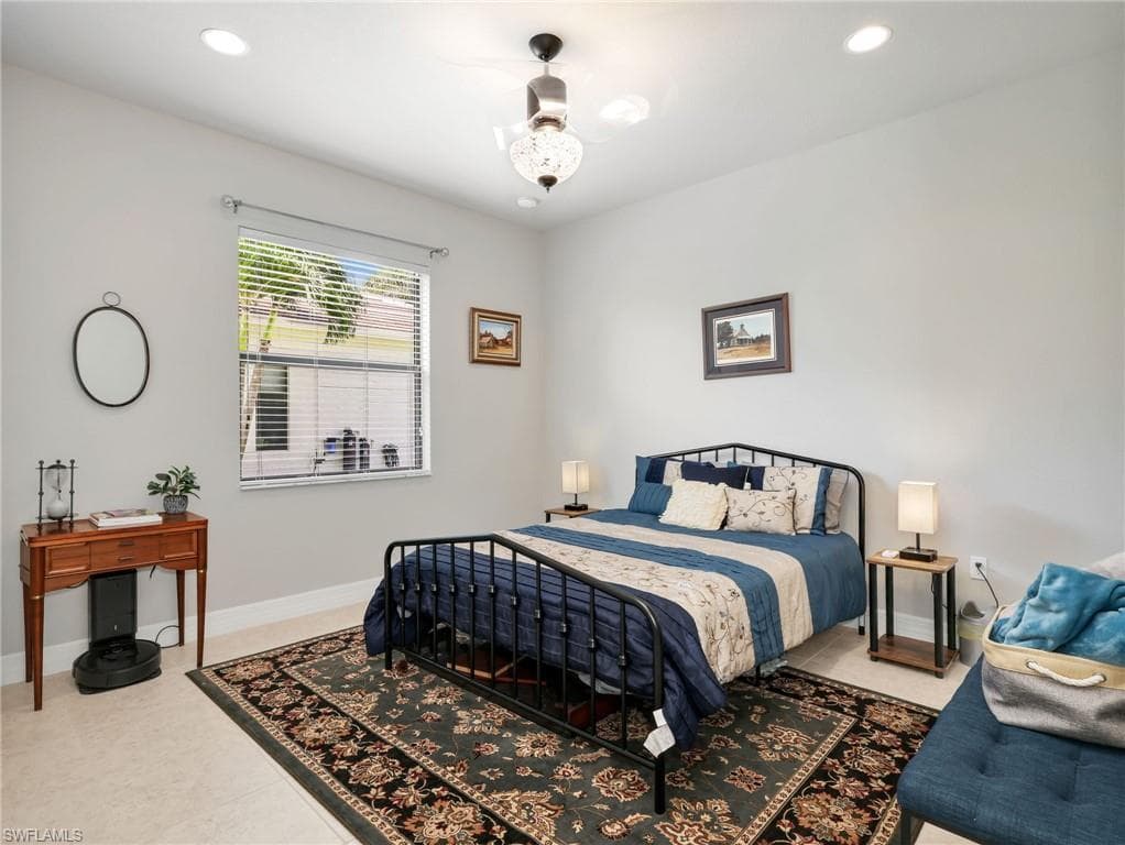 Spacious guest suite bedroom featuring recessed lighting, a ceiling fan with integrated light, tile flooring, and a large window with horizontal blinds