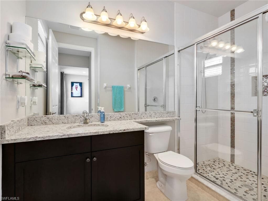 Bathroom featuring a dark wood vanity with a light speckled countertop, under-mount sink, and large wall-mounted mirror