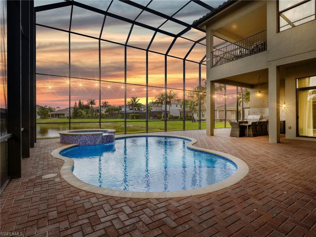 Screened lanai featuring a swimming pool and attached spa with mosaic tile detailing
