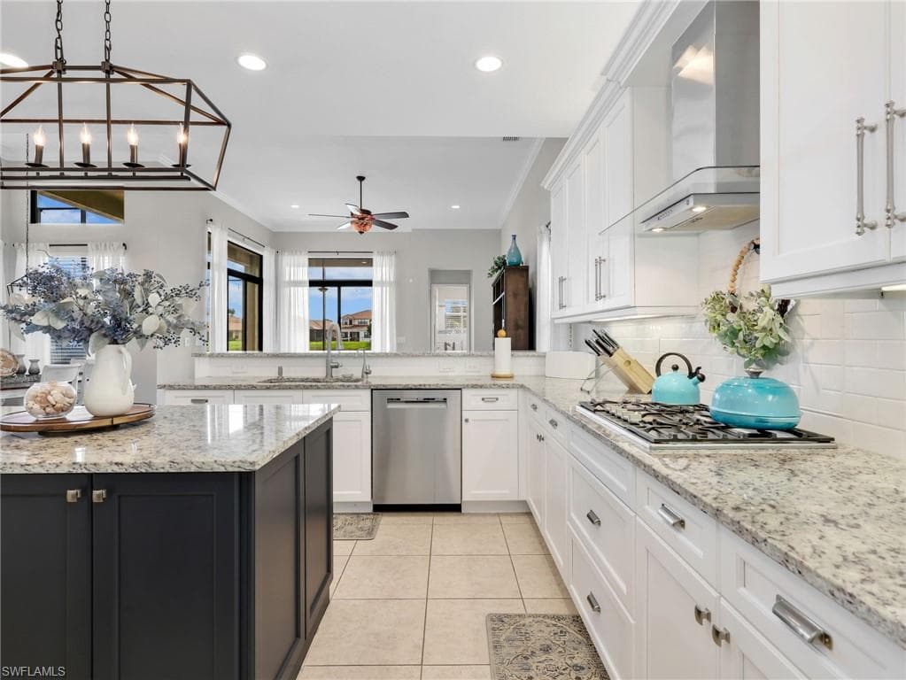 Gourmet kitchen featuring a central island with dark cabinetry, granite countertops, tile flooring, white shaker cabinets, and stainless steel appliances including a gas range and dishwasher