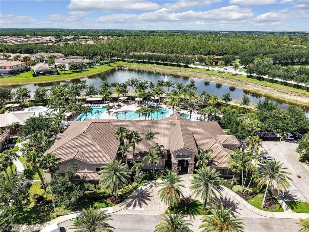 Community amenity building featuring a tile roof, multiple swimming pools, and extensive palm tree landscaping