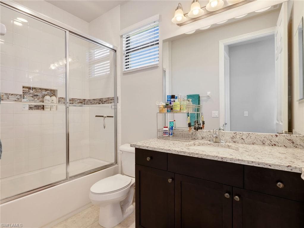 Bathroom featuring a built-in tub with a sliding glass shower door, a tile surround with decorative accent banding, and a recessed niche