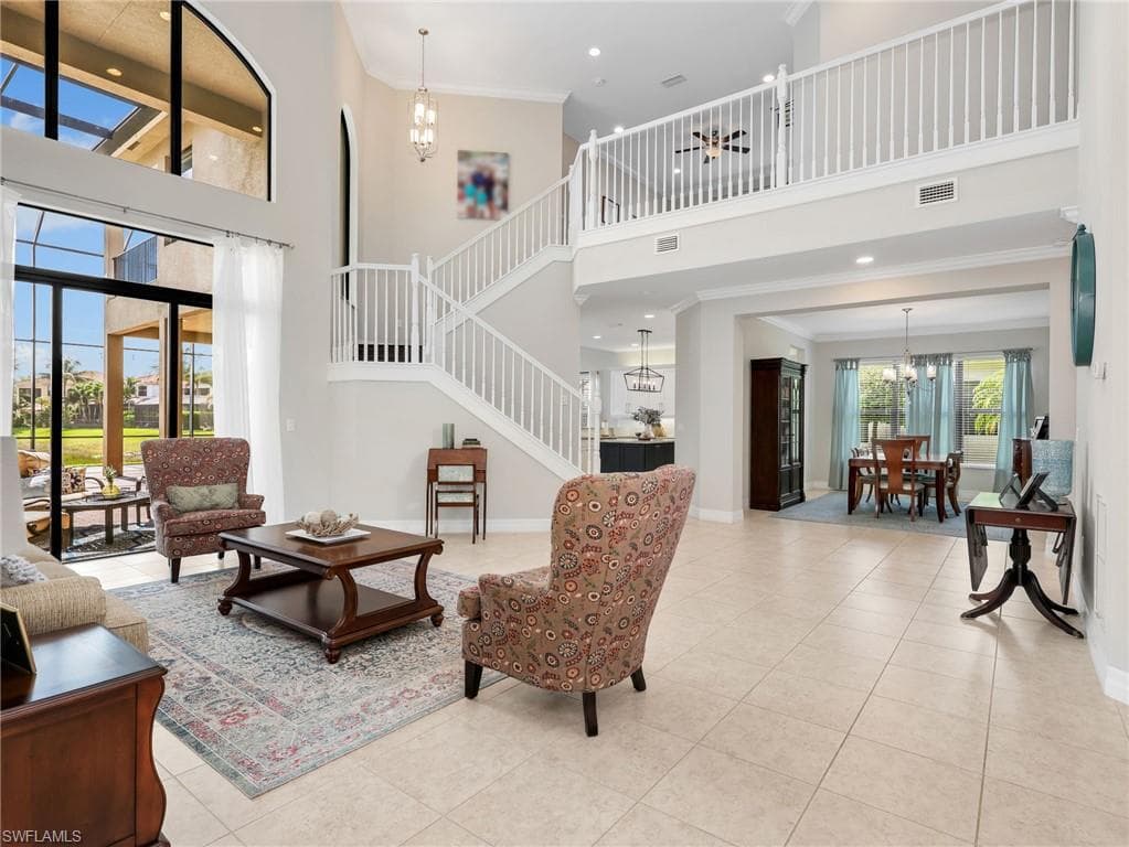 Grand living room with soaring ceilings, expansive two-story windows, and tile flooring