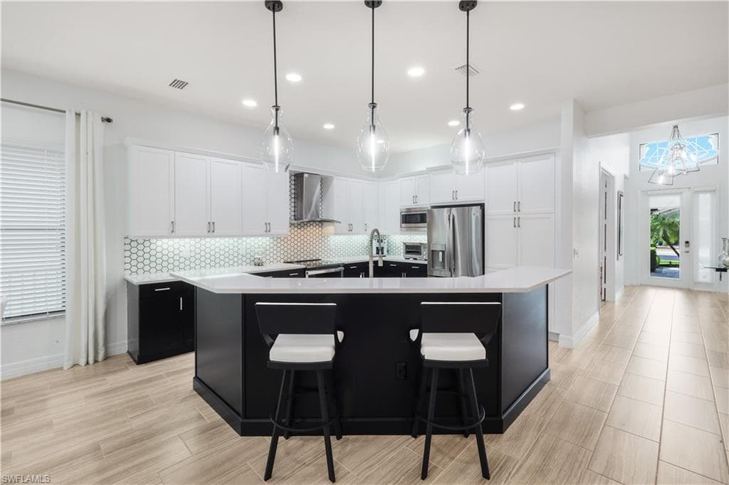 Renovated kitchen with quartz counter tops, wood cabinetry, stainless steel appliances, custom pendant lighting and tile floors.