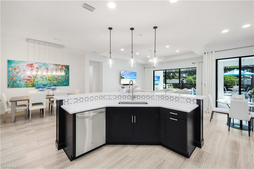 Fully renovated kitchen with stainless steel appliances, quartz countertops and custom backsplash with pendant lighting.