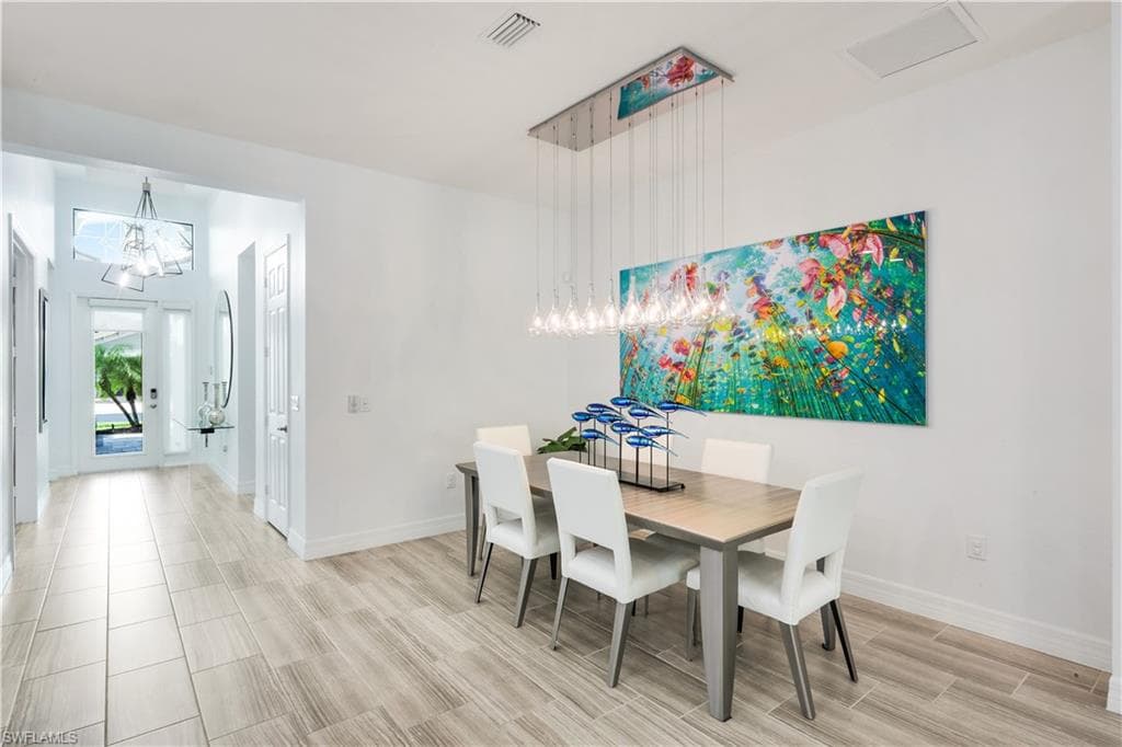 Dining area with custom lighting and hallway to front door access.