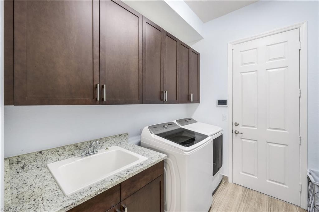 Laundry room with wood cabinetry, sink and washer & dryer leads to garage.