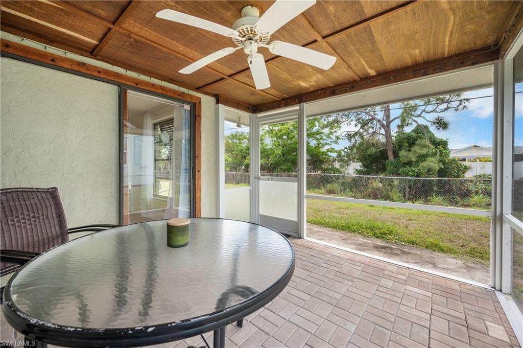 Screened lanai featuring paver flooring, a wood-finish ceiling with a ceiling fan, and sliding glass door access to the interior